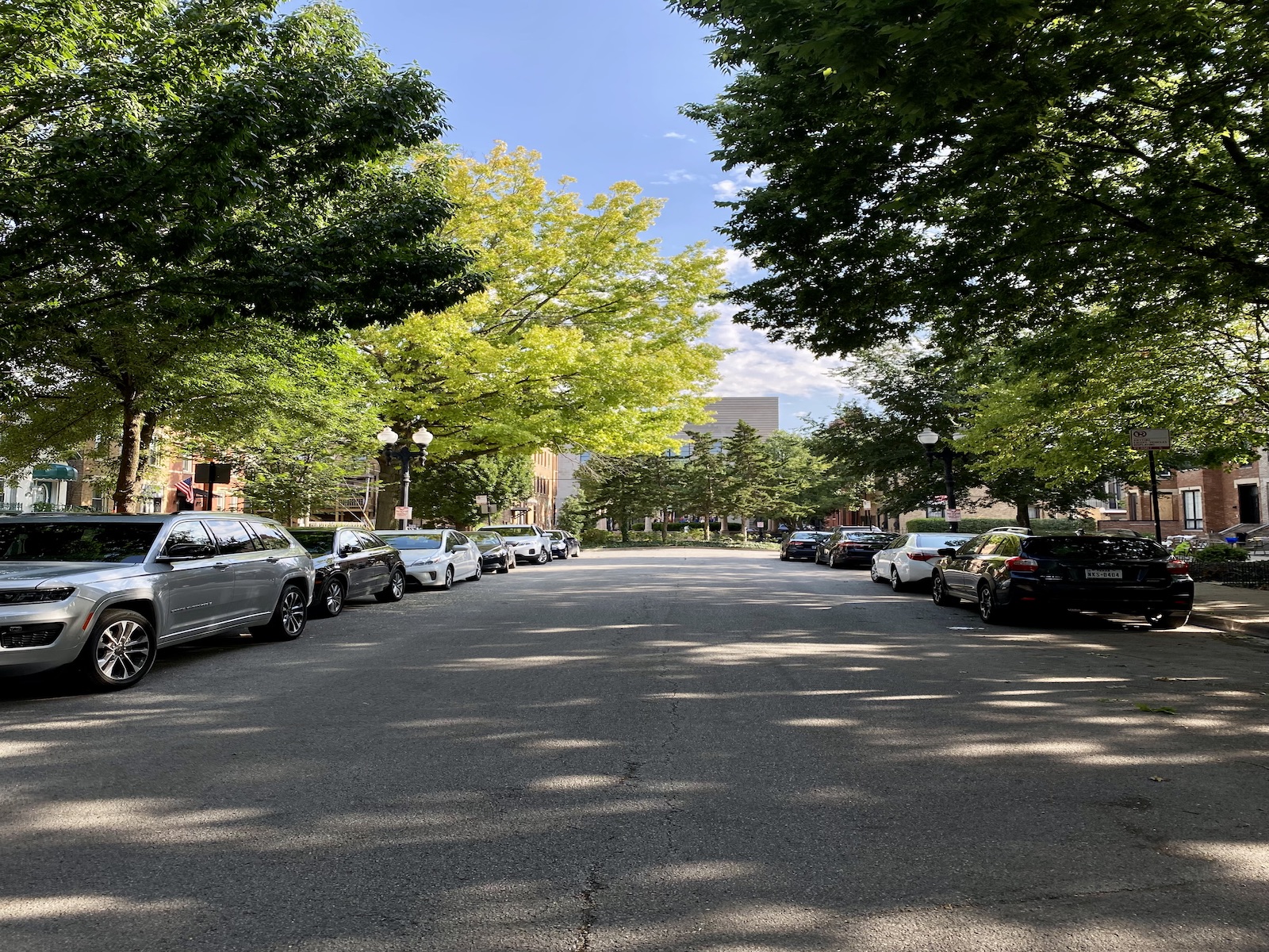 No outlet street with cars parked on both sides. The sidewalks are lined with trees.